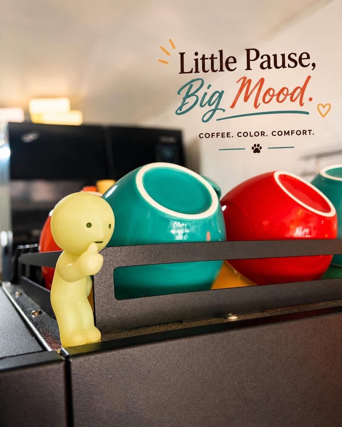 Colorful cups and a small yellow character beside the coffee machine.